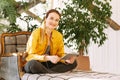 A young woman is sitting in a chair, working on a tablet and looking at the camera. Young businessman works at home