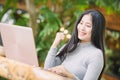 Young woman sitting in coffee shop at wooden table, drinking coffee and using laptop Royalty Free Stock Photo