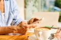 Young woman sitting in coffee shop at wooden table, drinking coffee and using smartphone.On table is laptop. Girl Royalty Free Stock Photo