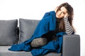 Young woman sitting on a couch, holding her head, having a strong headache covered blanket Royalty Free Stock Photo