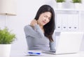 Young woman sitting at desk in front of laptop, touch neck feels pain Royalty Free Stock Photo