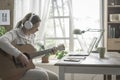 Woman playing guitar and connecting with her laptop Royalty Free Stock Photo