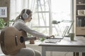 Woman playing guitar and connecting with her laptop Royalty Free Stock Photo