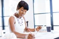 Young woman sitting at a desk in an office and working on blueprint Royalty Free Stock Photo