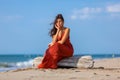 YOUNG WOMAN SITTING ON THE SAND OF THE BEACH Royalty Free Stock Photo