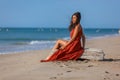 YOUNG WOMAN SITTING ON THE SAND OF THE BEACH Royalty Free Stock Photo