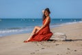 YOUNG WOMAN SITTING ON THE SAND OF THE BEACH Royalty Free Stock Photo