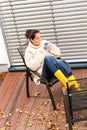 Young woman sitting drinking tea fall patio Royalty Free Stock Photo