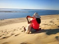 Young woman sitting on a dune photographing with smart phone beautiful landscape Royalty Free Stock Photo