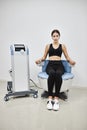 Young woman sitting on electromagnetic chair for stimulation of deep pelvic floor muscles and restoring neuromuscular control at