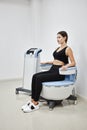 Young woman sitting on electromagnetic chair for stimulation of deep pelvic floor muscles and restoring neuromuscular control at Royalty Free Stock Photo