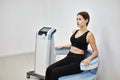 Young woman sitting on electromagnetic chair for stimulation of deep pelvic floor muscles and restoring neuromuscular control at