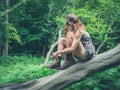 Young woman sitting on fallen tree in forest Royalty Free Stock Photo