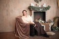 Young woman sitting by the fireplace in a cozy living room Royalty Free Stock Photo