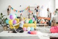 young woman sitting on floor with colorful balloons and her friends decorating