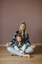 Young woman sitting on the floor in a living room with her little daughter in a lotus pose with closed eyes Royalty Free Stock Photo