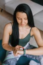 Young woman sitting on the floor and looking at her smartwatch in a cozy house Royalty Free Stock Photo