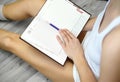 young woman sitting on floor and making notes to her diary Royalty Free Stock Photo