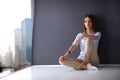 Young woman sitting on the floor near dark wall