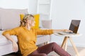 Young woman is sitting on floor by sofa, using laptop. Caucasian woman working Royalty Free Stock Photo