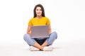 Young woman sitting on the floor and using laptop on white background Royalty Free Stock Photo