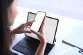 Young woman sitting in front of her tablet computer and using mobile phone. Royalty Free Stock Photo