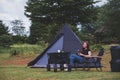 A woman sitting in front of a tent and enjoy camping in the outdoors Royalty Free Stock Photo