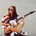 Young woman sitting on a ground with electric guitar Royalty Free Stock Photo