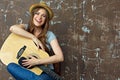 Young woman sitting with guitar on grunge wall background. Royalty Free Stock Photo