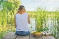 Young woman sitting with her back on wooden pier, copy space Royalty Free Stock Photo