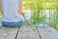 Young woman sitting with her back on wooden pier, copy space Royalty Free Stock Photo