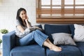 Young woman sitting on her sofa with pillow in hands. Young happy woman at home sitting on modern sofa in front of window relaxing Royalty Free Stock Photo