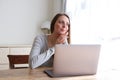 Young woman sitting at home with laptop and looking out of window Royalty Free Stock Photo