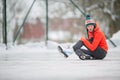 Young woman sitting on the ice rink after falling down