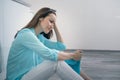 Young woman sitting on kitchen floor holding her head and crying, upset, sad, depressed Royalty Free Stock Photo