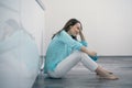 Young woman sitting on kitchen floor holding her head and crying, upset, sad, depressed Royalty Free Stock Photo