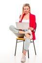 A young woman is sitting with laptop, legs crossed and smiling at something, looking at the screen. Isolation on a white