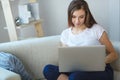 Young woman sitting with laptop on sofa at her home Royalty Free Stock Photo