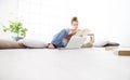 Young woman sitting in living room reading a book with your computer nearby, stay at home concept