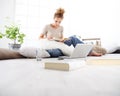 Young woman sitting in living room reading a book with your computer nearby, stay at home concept