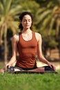 Young woman sitting in lotus position doing yoga in park Royalty Free Stock Photo