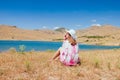 Young woman sitting on meadow near lake