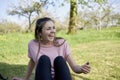 Young woman sitting in a meadow in spring laughing and having lots of fun in the background fruit trees Royalty Free Stock Photo