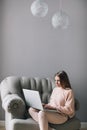 Young woman sitting on modern chair at home working on laptop. Royalty Free Stock Photo