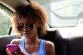 Young woman sitting n backseat of car looking at cell phone