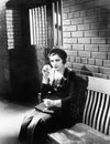 Young woman sitting n a bench in front of a jail cell