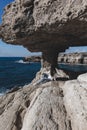 Young woman is sitting near cave hole and looking at sea near cape Greco Royalty Free Stock Photo