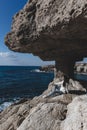 Young woman is sitting near cave hole and looking at sea near cape Greco Royalty Free Stock Photo