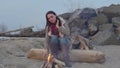 Young woman sitting near the fire in the evening