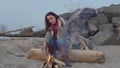 Young woman sitting near the fire in the evening fire.